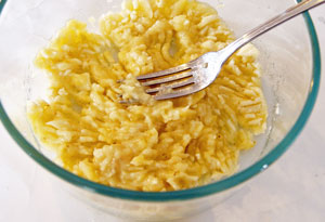 mashing banana for coconut pineapple cake